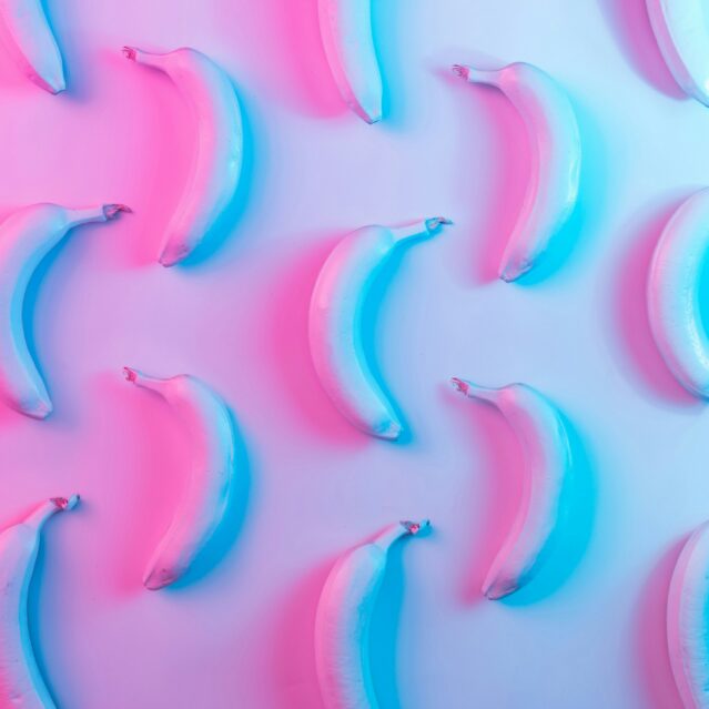 Bananas glowing in pink and blue on a plain surface
