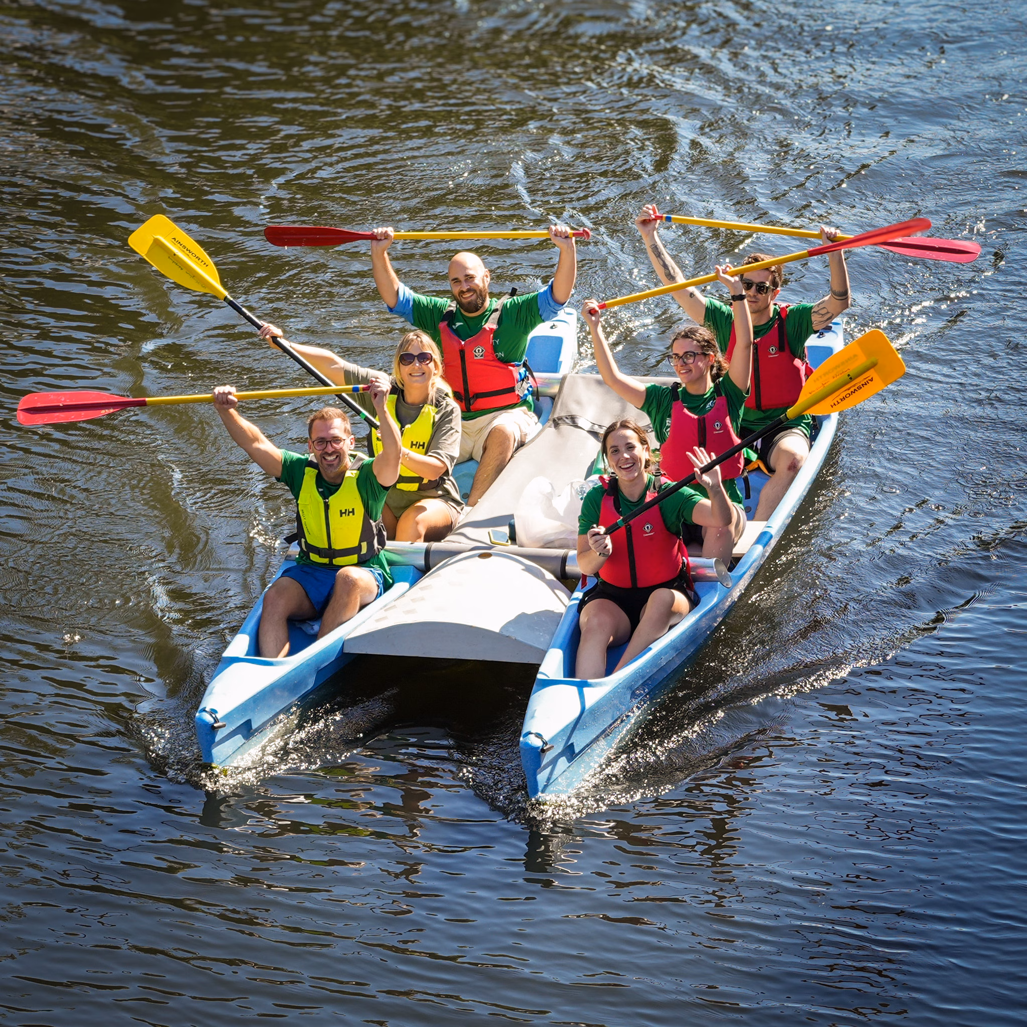 Team rowing with paddles in the air